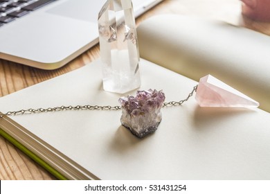 White Notebook On Wooden Table With Crystals And Laptop