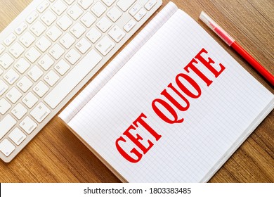 a white notebook with the text Get Quote lies on a wooden surface near a white keyboard with a red marker - Shutterstock ID 1803383485