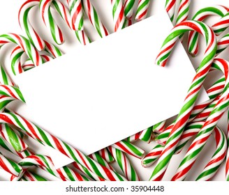 A white note-card, greeting card, or invitation surrounded by brightly color Christmas Candy Canes with copy space