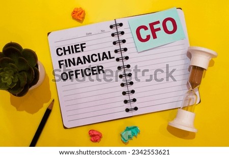 A white notepad with the text CFO Chief Financial Officer, written on a white notepad next to red pens, pencils and markers on a black background.