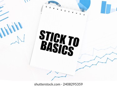 White notepad with text STICK TO BASICS on the financial documentation. Finance and business concept