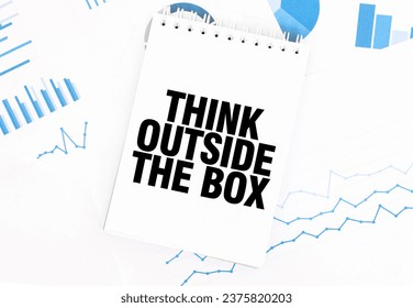 White notepad with text THINK OUTSIDE THE BOX on the financial documentation. Finance and business concept