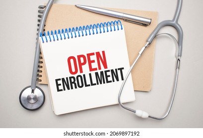 White notepad with the words open enrollment and a stethoscope on a blue background. Medical concept - Shutterstock ID 2069897192