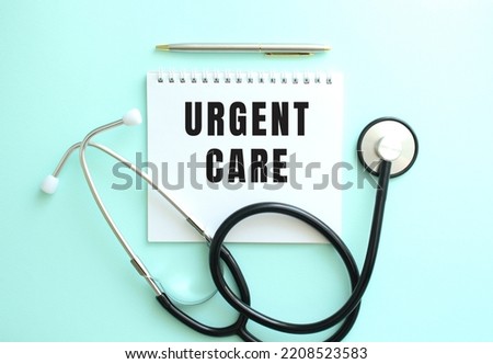 White notepad with the words URGENT CARE and a stethoscope on a blue background. Medical concept