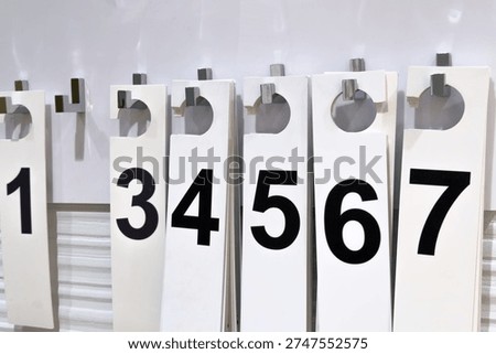 White numbered paper identification tags with bold black digits hanging sequentially on metal hooks