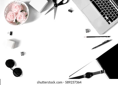 White office desk frame with laptop keyboard and supplies. Laptop, notebook, pen, roses, sunglasses, clips, pencil, scissors, watch and office supplies on white background. Flat lay, top view, mockup