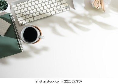 White office desk with notebook, keyboard, pencil holder and cup of coffee. Top view with copy space for your text.