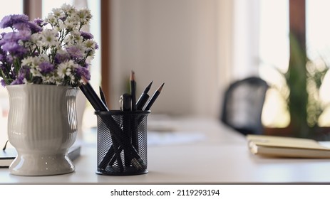 White Office Desk With Pencil Holder, Notebook And Flower Bouquet In Pot.