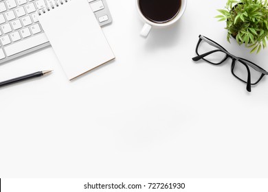 White office desk table with blank notebook, computer keyboard and other office supplies. Top view with copy space, flat lay. - Shutterstock ID 727261930
