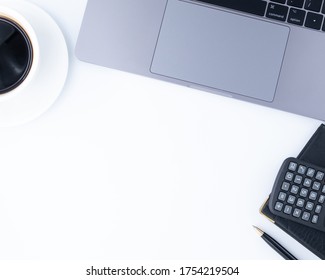 White Office Desk Table With Calculator, Blank Mockup Screen Notebook, Black Coffee, Pen And Supplies. Top View With Copy Space, Flat Lay.