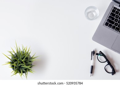 White Office Desk Table With Laptop, Smartphone, And Glass. Top View With Copy Space, Flat Lay.