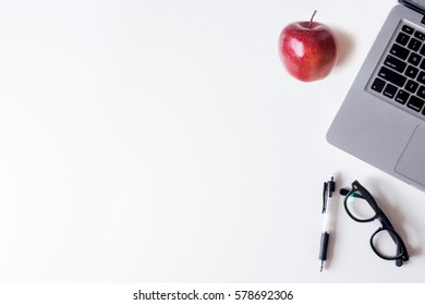 White Office Desk Table With Laptop, Smartphone, And Apple. Top View With Copy Space, Flat Lay.