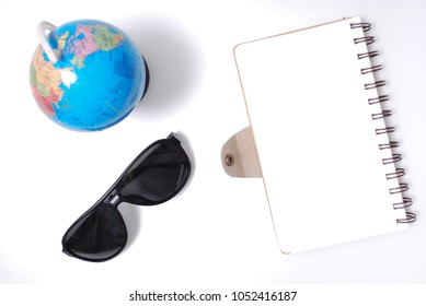 White Office Desk Table With Open Note Book, Globe And Sun Glasses . Top View With Copy Space, Flat Lay.