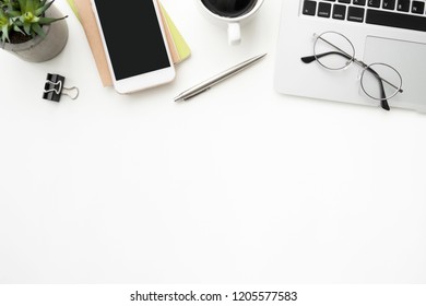 White office desk table with smartphone, laptop computer and supplies. Top view with copy space, flat lay. - Shutterstock ID 1205577583