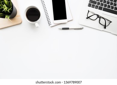 White office desk table with smartphone with blank mock up screen, laptop computer, cup of coffee and supplies. Top view with copy space, flat lay. - Shutterstock ID 1369789007