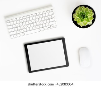 White Office Desk Table With Tablet Pc Computer In Ipade Style With Blank Screen, Wireless Aluminum Keyboard, Mouse And Succulent Flower In Pot. Top View With Copy Space. Flat Lay.