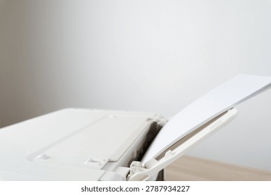 White office printer with a stack of blank A4 paper loaded in the feeder tray, shown in a clean minimalist workspace. Conceptual image for printing, office equipment, productivity and documentation.