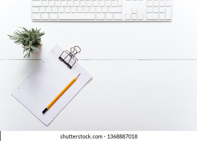 white office table, computer keyboard and little lavender plant, note papers, pencil