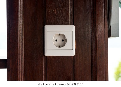 White old plastic power socket on a wooden wall outside. Bali.