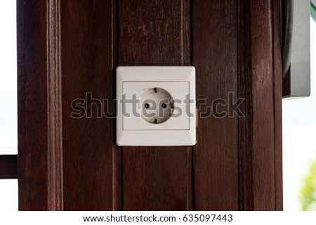 White old plastic power socket on a wooden wall outside. Bali.