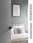 White opened door in bedroom with made bed and minimalist interior. Concepts of cleaning service, hospitality, comfort staying in hotel. Room with wall decor. Template picture frame, art poster