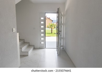 White opened entrance door and marble tiled floor in front of green lawn with palm tree - Powered by Shutterstock