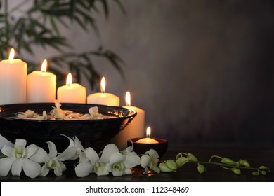 White orchid flower, burning candle and bamboo leaves on grunge background,Zen concept.