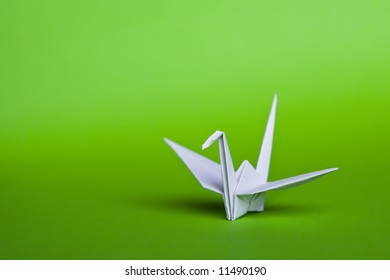 A White Origami Crane On A Green Background