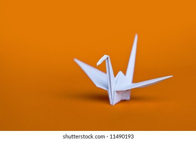 A White Origami Crane On An Orange Background