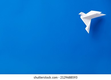 White Origami Paper Dove Flying Against A Blue Background.