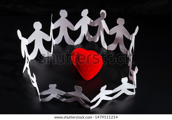 White origami people are staying\
around red bright heart. International Human Solidarity\
Day