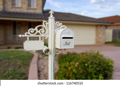 White Ornamental Letter Box With A Facility To Write House Number And A Newspaper Holder In Front Of A Beautiful House