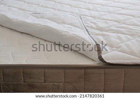 White orthopedic mattress top side surface pattern on unmade bed in the bedroom. Hypoallergenic foam mattress for proper spinal alignment and pressure point relief. Background, copy space, close up.