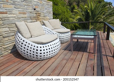 White Outdoor Furniture Round Rattan Armchairs And Glass Table On Wood Resort Terrace, Greece