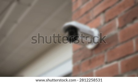 A white outdoor security camera is mounted on a textured red brick wall, providing surveillance and protection for a property.