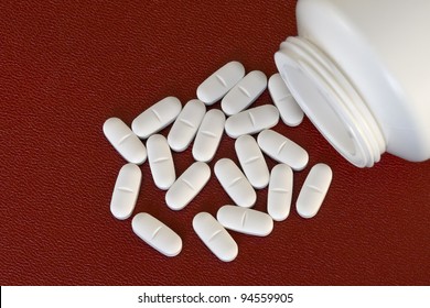 White, Oval Pills And Pill Bottle On A Red Background.