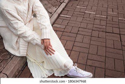 White Oversized Sweater, Light Skirt And White Sneakers. Details Of Women's Street-style Clothing.