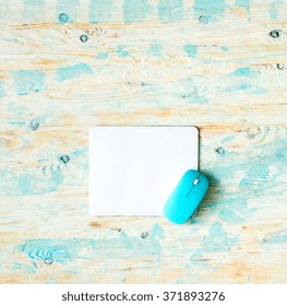 White Pad With Blue Mouse On Colorful Wooden Background