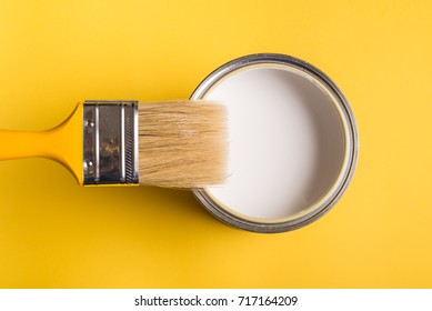 White Paint Can With Brush Top View On Yellow Background.