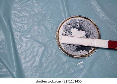 White Paint Can Lid With Stirring Stick And Light Blue Floor-protecting Tarp