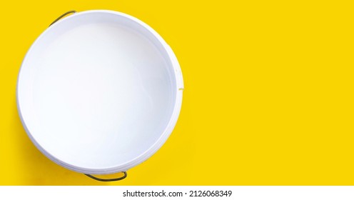 White Paint In Plastic Bucket On Yellow Background.