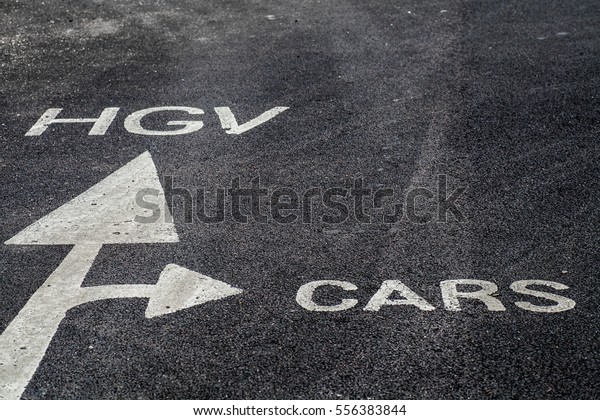 White painted arrow on the tarmac directs cars and\
trucks to different areas