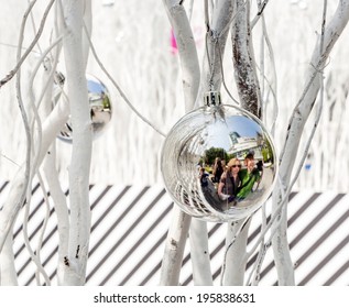 White Painted Branches Give A Harmonic Background With Chrismas Tree Balls And Mirroring Of A Family