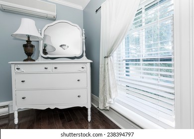 White Painted Dresser With Mirror And Lamp Near Window Interior