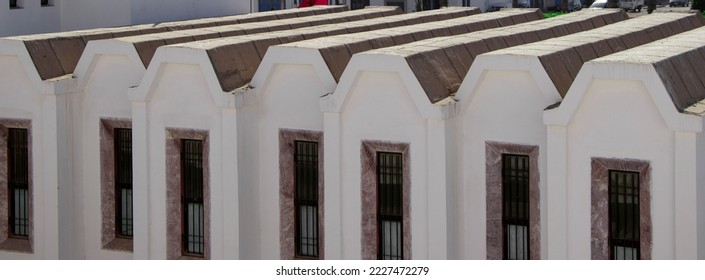 White painted façade of a modern building with a particular design roof. Modern and creative architecture - Shutterstock ID 2227472279