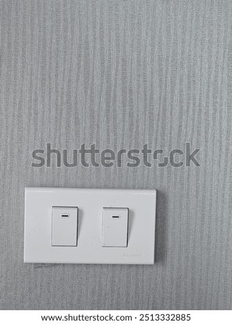 A white Panasonic light switch is mounted on a textured gray wall.