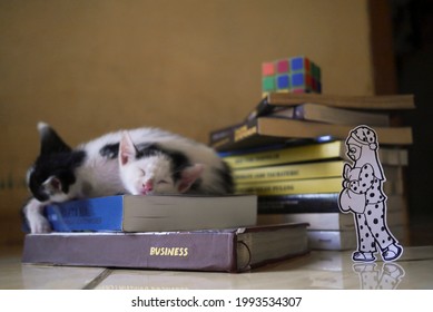 White Paper Artwork Of A Girl In Polkadot Pajama With A Night Cap And Pillow Walking Towards Cute Cats That Sleeping On A Stack Of Books