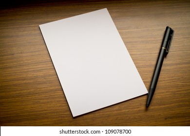 White Paper With Black Pen On Wooden Table