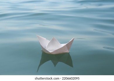 White Paper Boat Floating On Water Surface