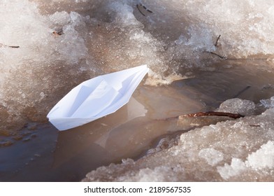 A White Paper Boat Sails Along A Spring Stream Among The Snowy Shores